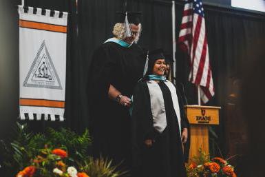 A graduate student receives their hood from Dr. Deb Stuto on the platform at Doane's winter commencement ceremony on Saturday, Dec. 16. 